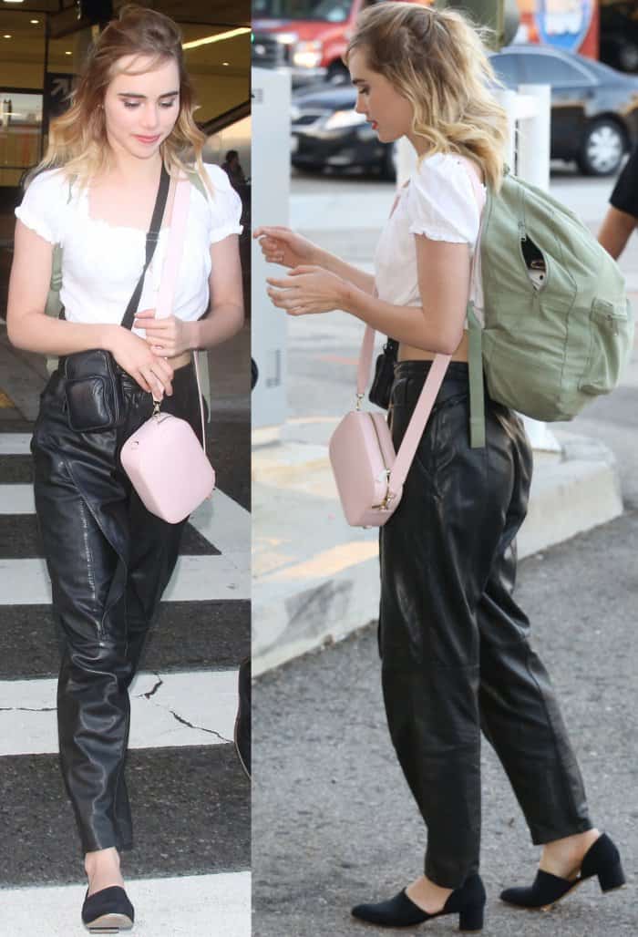 Suki Waterhouse arriving at LAX in a cream-colored crop top, black leather pants, and Mansur Gavriel d'Orsay heels