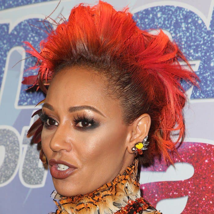 Mel B showing off her bright orange hair with feathers intertwined throughout