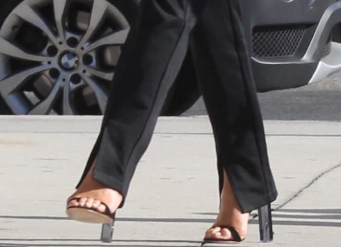 Chrissy Teigen wearing black ankle-strap sandals with clear heels while out and about in LA
