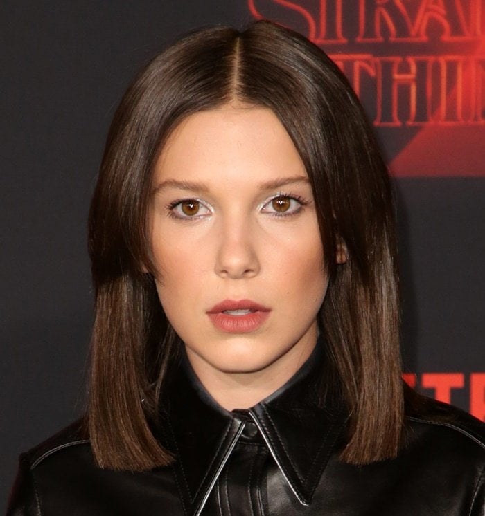 Millie Bobby Brown with shoulder-length straight hair parted down the middle