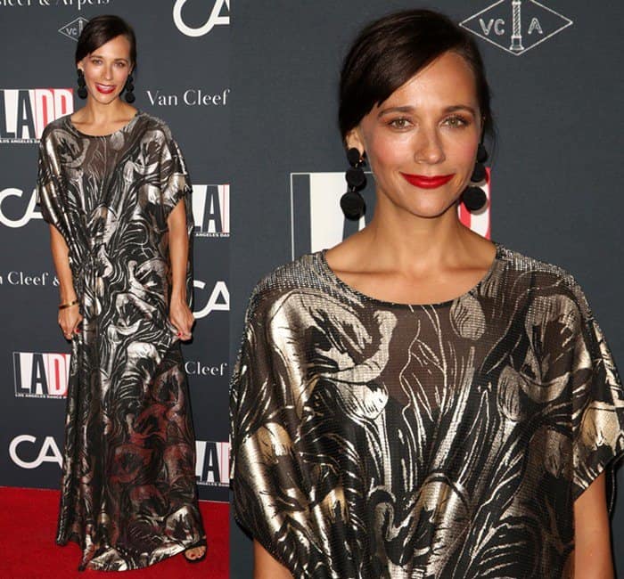 Rashida Jones wore a floor-length sheer black and silver metallic dress with side ruching, styled with black open-toe heels, Rebecca Vallance earrings, a sleek updo, and bold red lips