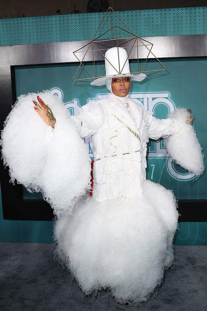 Erykah Badu commands attention in an ethereal Thom Browne ensemble featuring dramatic cloud-like tulle, a gold geometric hat, and avant-garde details
