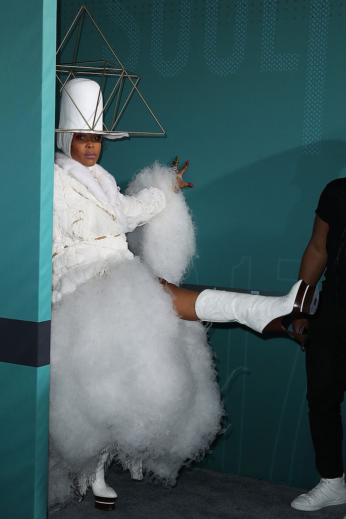 Erykah Badu playfully shows off her striking white cowboy boots with towering wooden platform heels