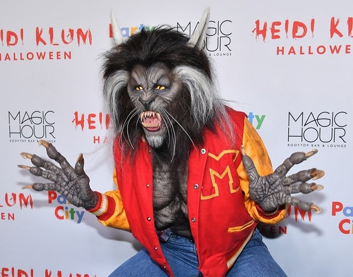 Heidi Klum fully embodies a werewolf from Michael Jackson's Thriller video, complete with a varsity jacket, intricate prosthetics, and claws, at her annual Halloween party