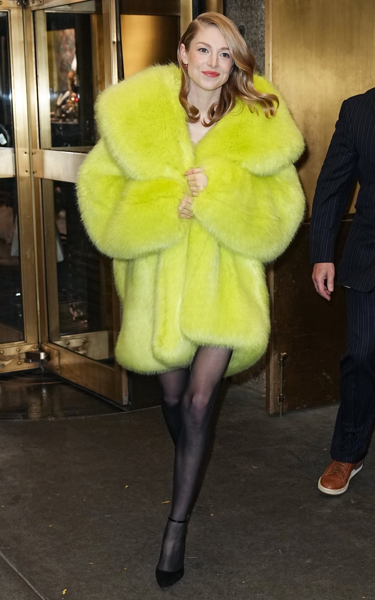 Hunter Schafer wore a vibrant yellow hooded fur coat from Alexandre Vauthier's Fall 2023 collection, paired with sheer black tights and black ankle strap pumps, during her appearance on "The Tonight Show with Jimmy Fallon" on November 17th to promote "The Hunger Games: The Ballad of Songbirds & Snakes"