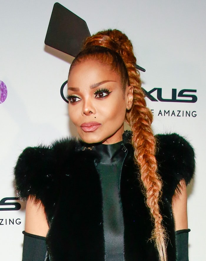 Janet Jackson stunned with a voluminous fishtail braid and statement paddle hair accessory, complemented by bold winged eyeliner and soft, nude-toned makeup