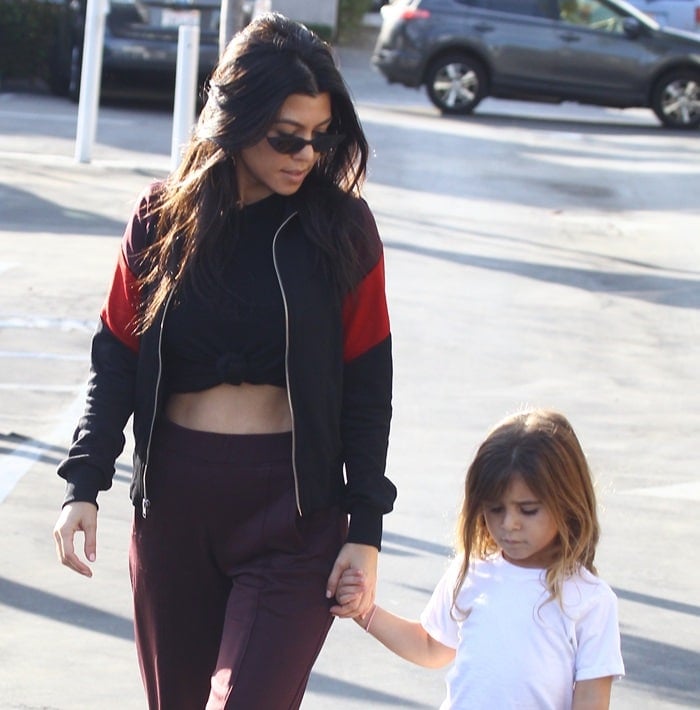 Kourtney flashed her impressive abs in a knot front t-shirt paired with high-waisted dark maroon pants