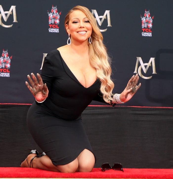 Mariah Carey dazzles in a black dress and diamonds while proudly showcasing her cement-covered hands