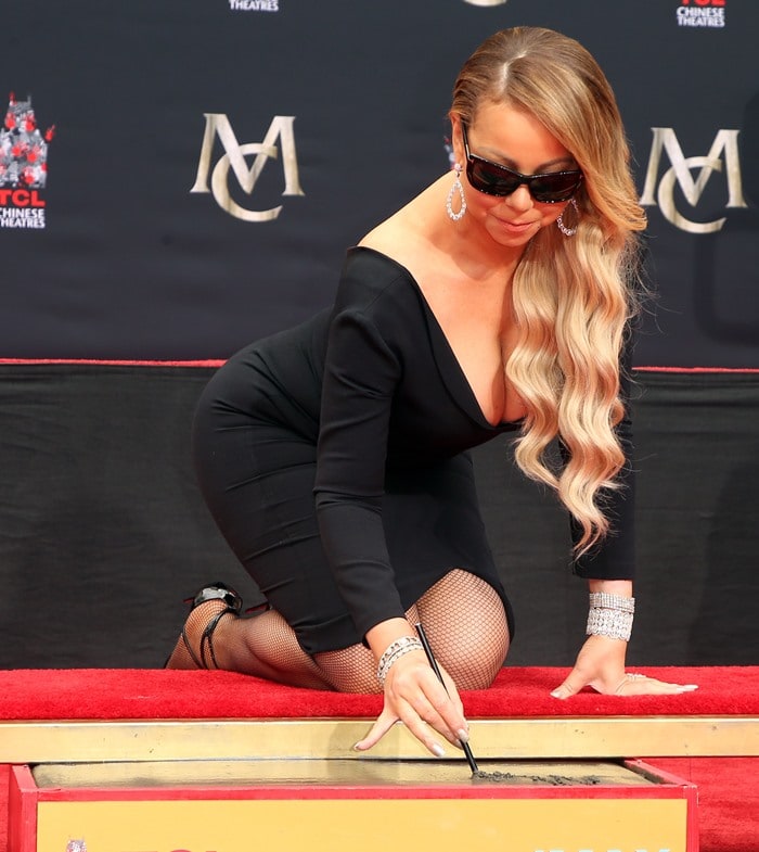 Mariah Carey wearing a glamorous black dress, fishnets, and dazzling diamond earrings