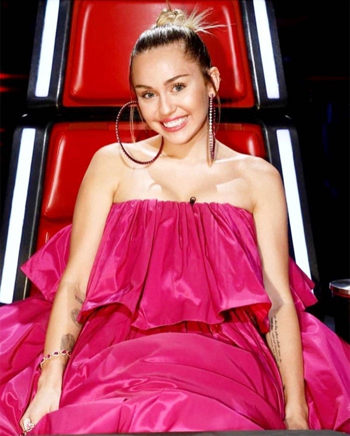 Miley Cyrus' Instagram pics of her wearing an Agatha Ruiz De La Prada spring 2018 pink tiered-ruffle strapless dress and pink satin chunky platform sandals on a live episode of "The Voice" on November 21, 2017.