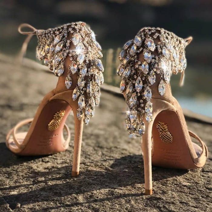 These beige suede ankle-tie sandals are embellished at the heel counter with dangling crystals in a silvertone setting