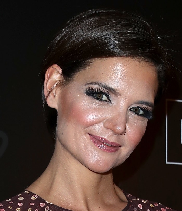 Katie Holmes wears a short side-parted hairstyle and heavy eye makeup