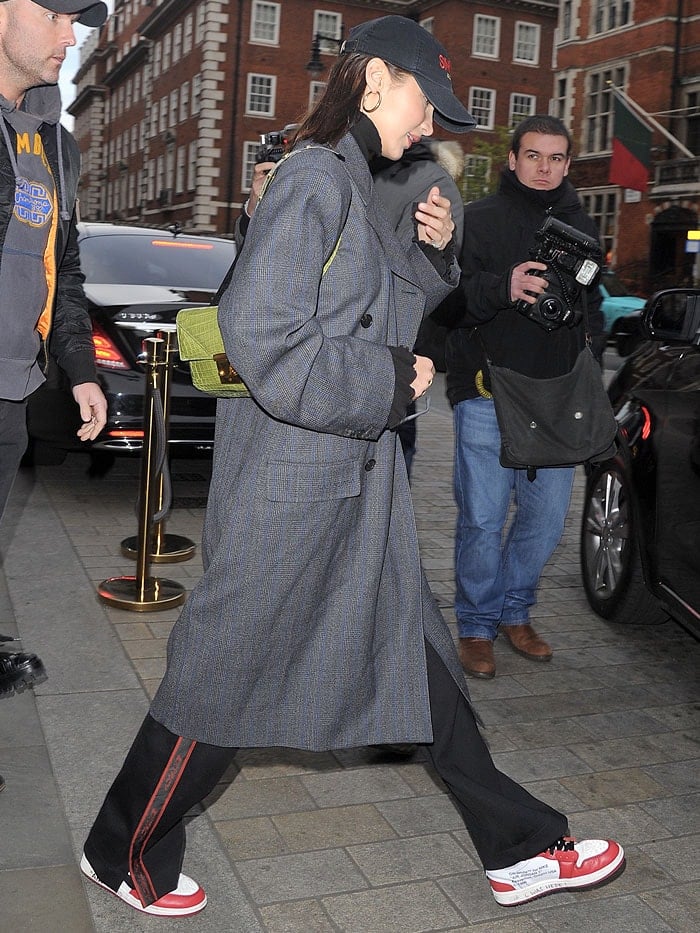 Bella Hadid wears a Balenciaga Pulled double-breasted coat with Misbhv Extacy side bands techno jersey pants and a Balenciaga Sinners cap