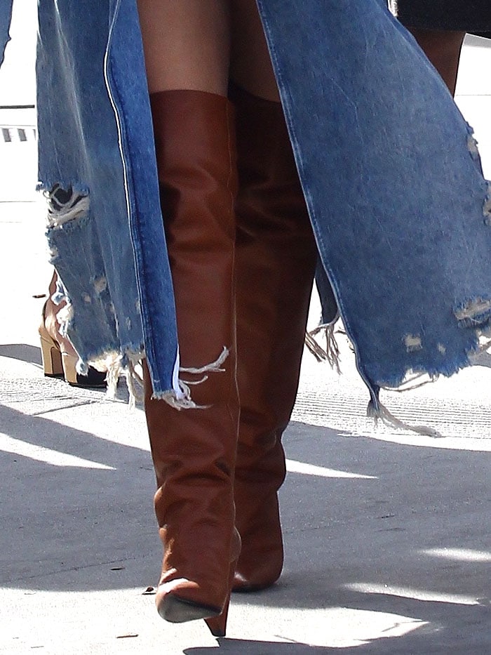 Closeup of Chrissy Teigen's Saint Laurent 'Niki' thigh-high boots in cognac leather.