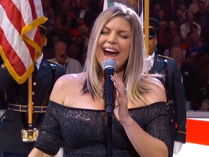 Fergie wearing a black lace off-shoulder dress and Casadei ankle-strap sandals to sing the national anthem.