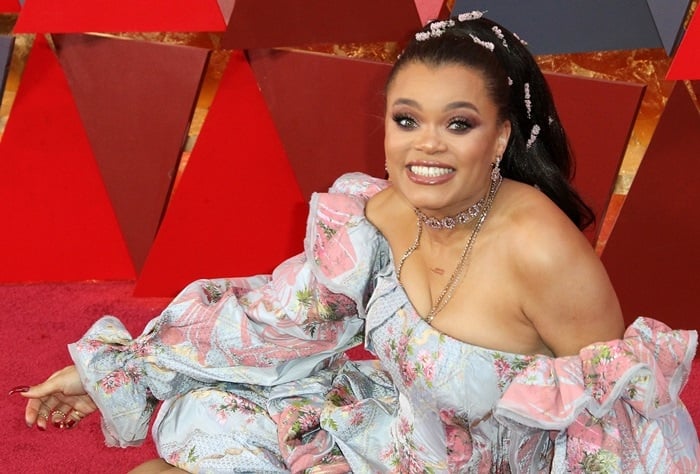 Andra Day posing horizontally on the red carpet