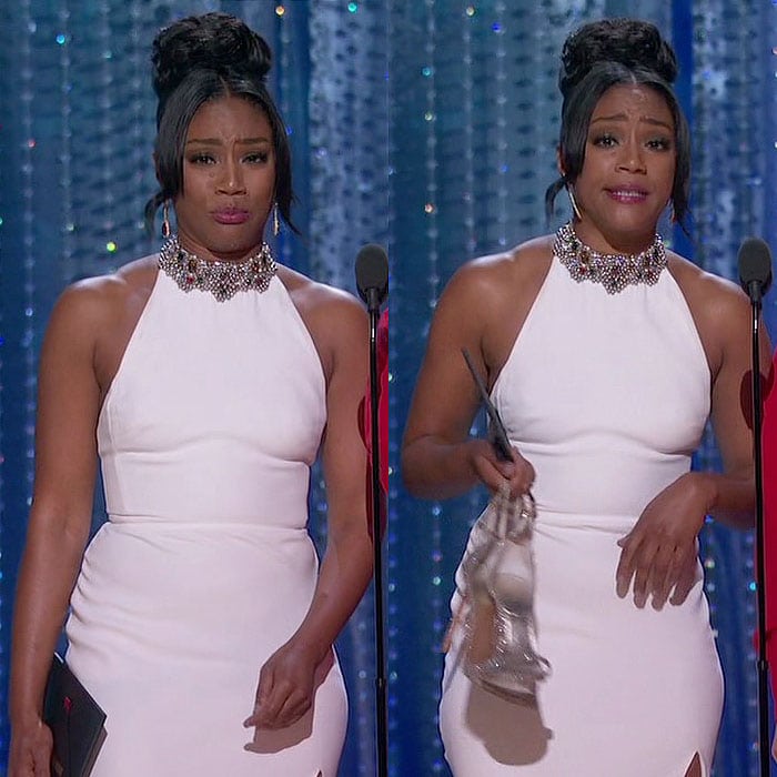Tiffany Haddish wearing her white Alexander McQueen dress for the third time and carrying her Stuart Weitzman "Nudist" sandals while presenting during the 2018 Academy Awards