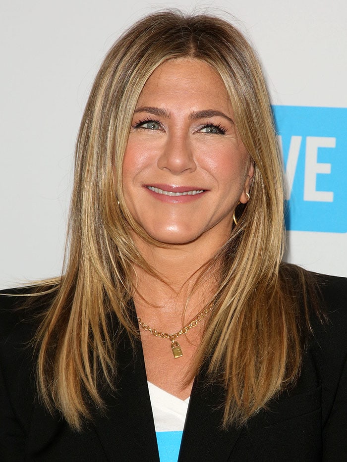 Jennifer Aniston shines with her signature layered hairstyle and a stylish gold padlock necklace at the WE Day California event
