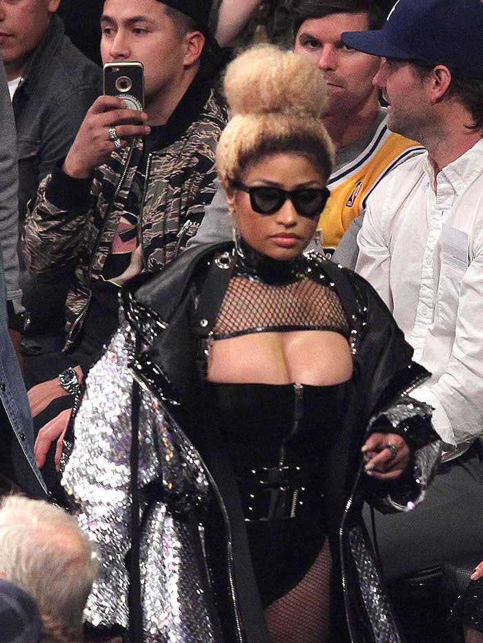 Nicki Minaj turning heads in a black latex zip bodysuit, fishnets, silver metal studs, and a scaly, silver hooded coat with black patent strips.