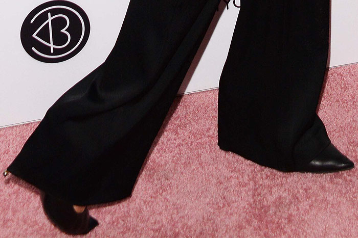 A close-up of Paris Hilton's Tom Ford black leather pumps featuring a striking gold metal heel, elegantly paired with her wide-leg pants at Beautycon 2018