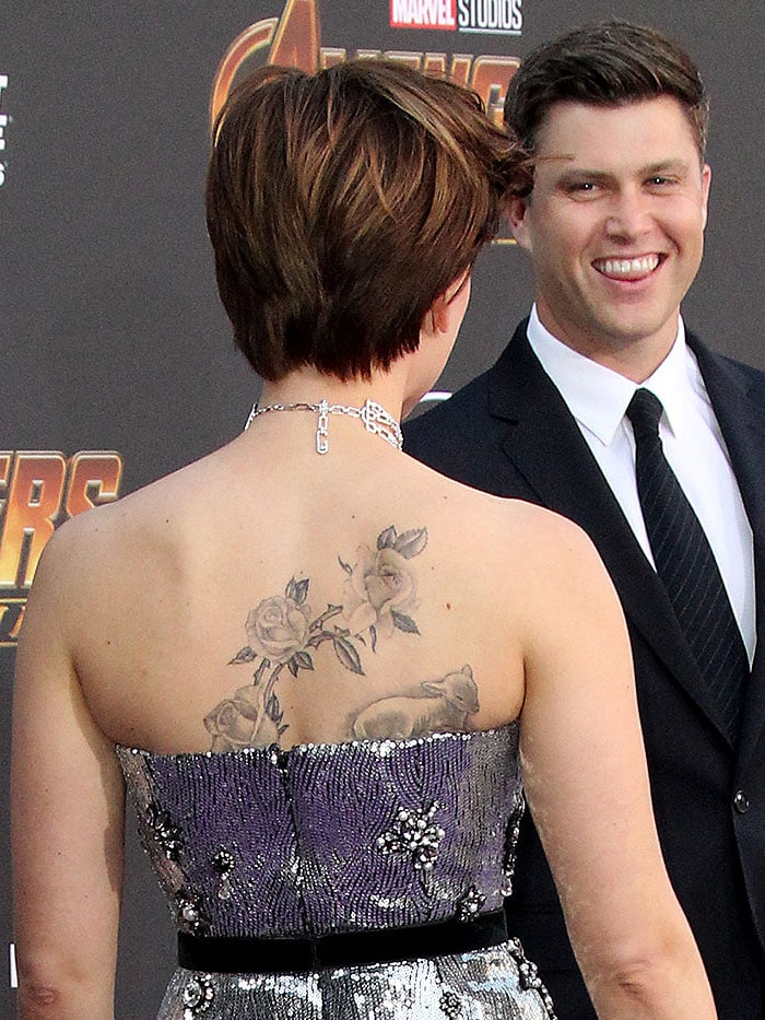 Scarlett Johansson turns her back to the cameras and shows an additional rose branch design to her previous lamb back tattoo while her boyfriend Colin Jost looks on