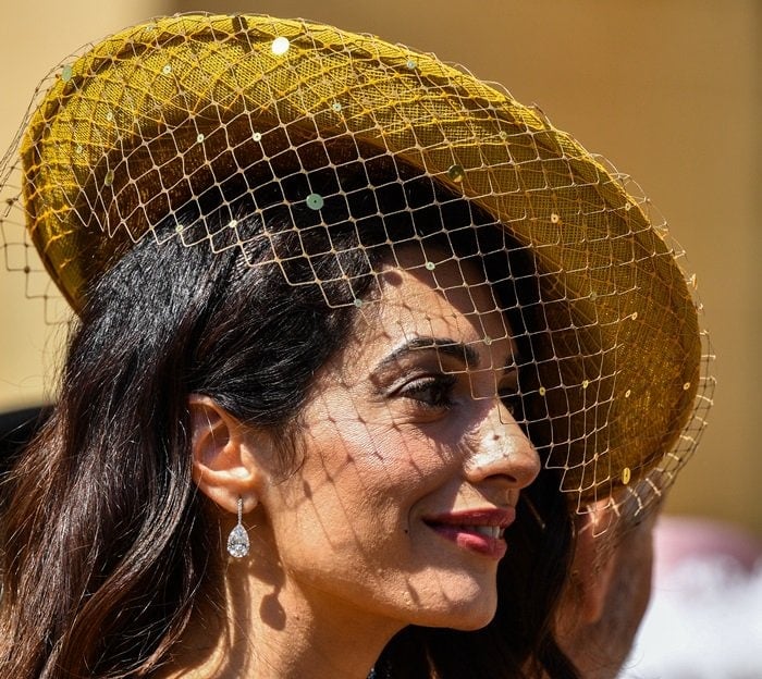 Amal Clooney completed her ensemble with a netted headpiece by Stephen Jones