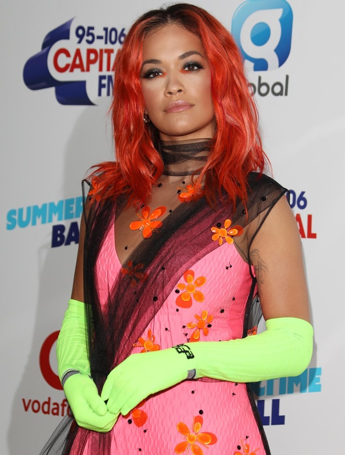 Rita Ora's fiery red locks matched the vivid energy of her neon green gloves, while her floral hot pink dress with a sheer black tulle overlay added avant-garde flair