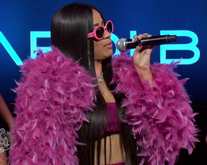 Cardi B dazzles in a pink feathered ensemble and matching sunglasses as she performs, effortlessly switching between singing in both Spanish and English, showcasing her bilingual talents