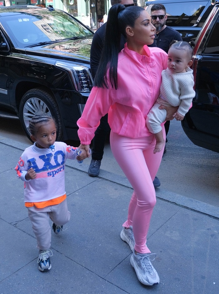 Kim Kardashian with Chicago in her arms and Saint holding her hand