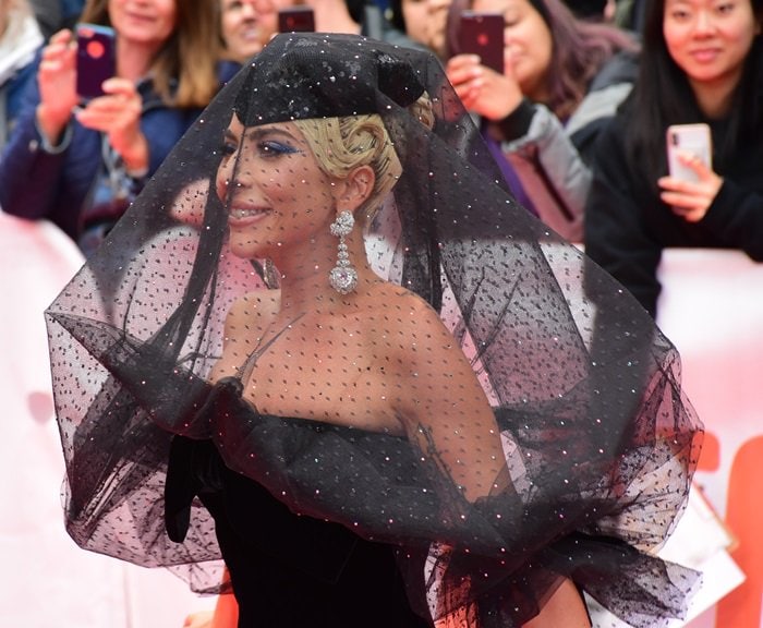 Lady Gaga shows off her “Garden of Kalahari” diamond pendant Chopard earrings and a black sequined hat