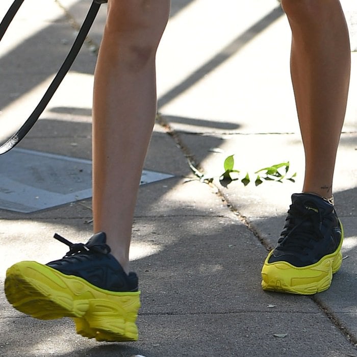 Hailey Baldwin wears navy and neon yellow Adidas by Raf Simons Ozweego sneakers