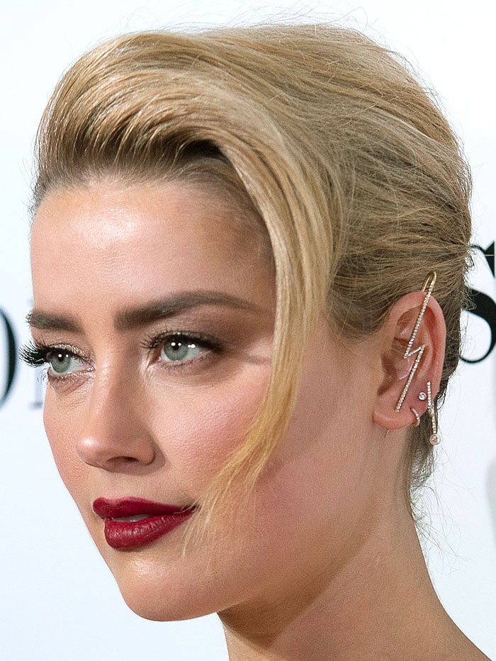 Closeup of Amber Heard's selection of earrings including a gold-and-diamond lightning piercing