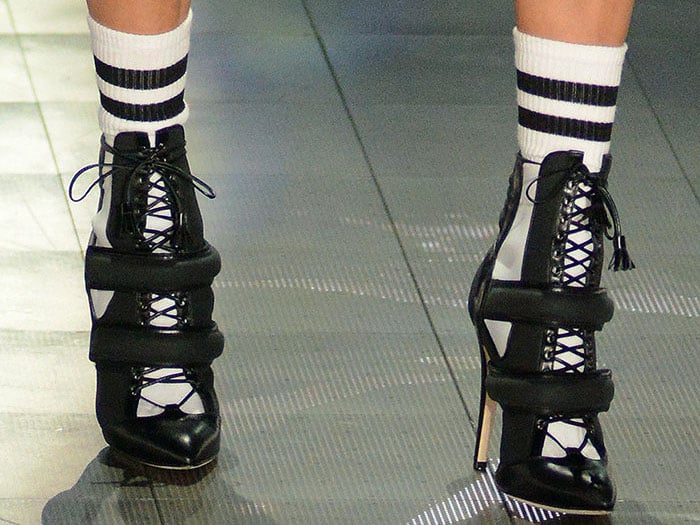 Closeup of Bella Hadid's classic striped socks and sporty black-and-white lace-up booties with two padded straps across the front