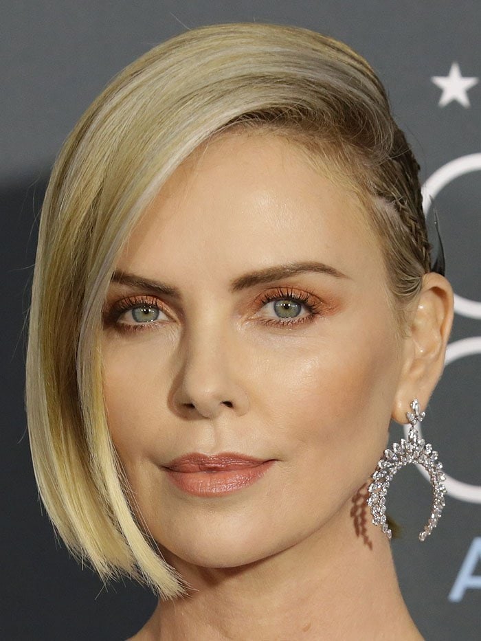 Charlize Theron wearing Messika 'Moonlight' high jewelry earrings and a custom Givenchy silver metal halo at the back of her half-slicked-back hairdo by Adir Abergel