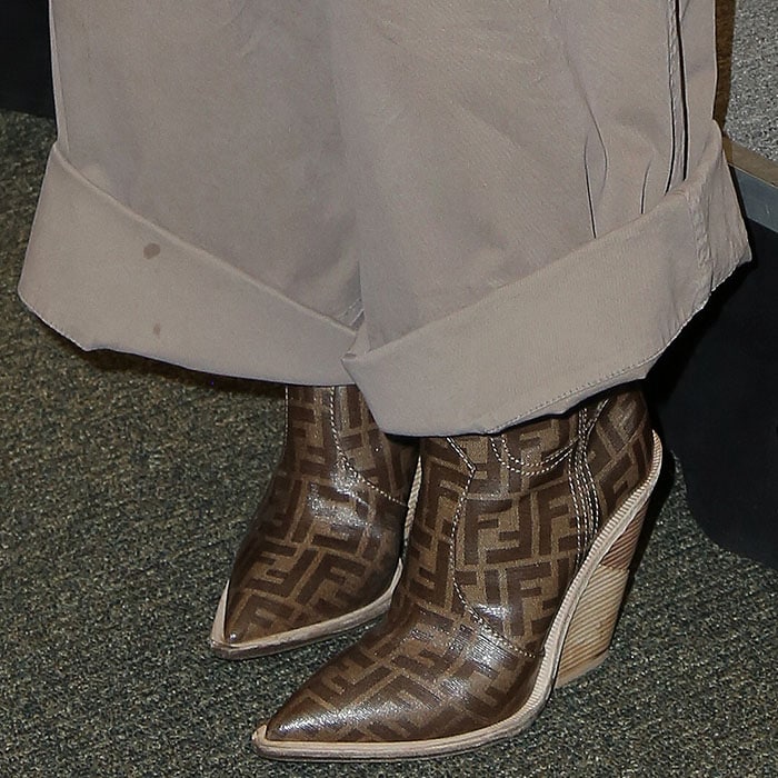 Closeup of Gwyneth Paltrow's Fendi logo-print cowboy boots and wide-leg khaki pants with stains on the rolled cuffs