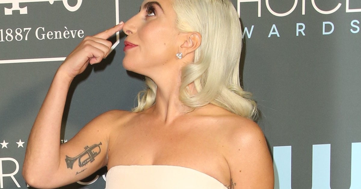 Lady Gaga Flashes Trumpet Tattoo On Right Arm in Grecian Style Dress