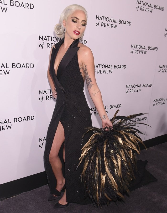 Lady Gaga toted a gigantic hand painted gold and ebony feather cape