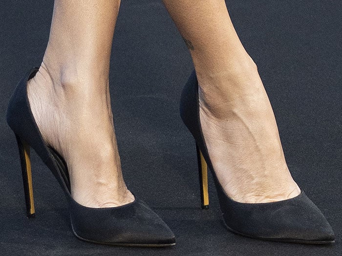 Close-up view of Penélope Cruz's black satin pumps featuring sleek stiletto heels for an elegant finish