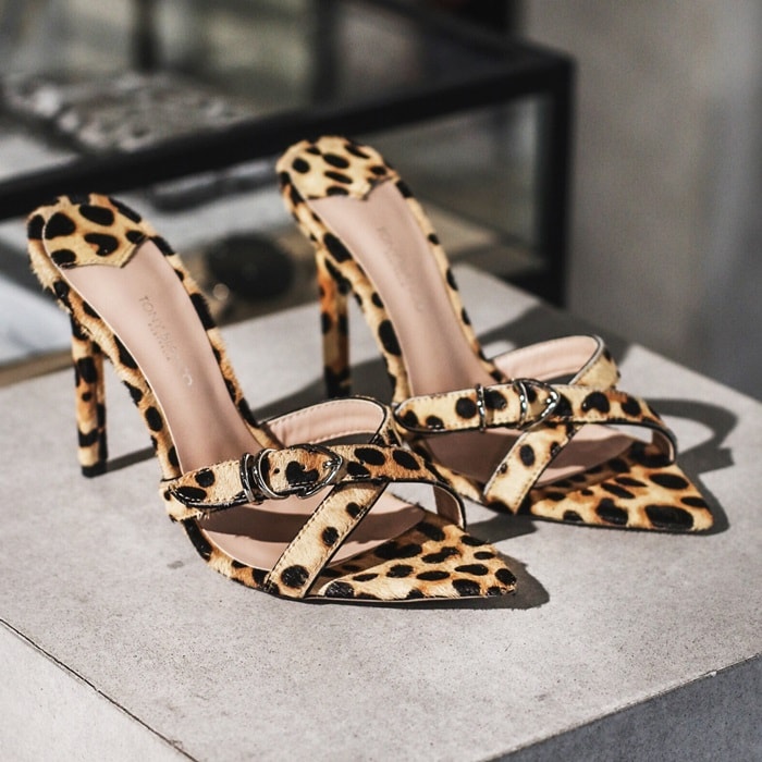 A tan leopard print pony hair stiletto heel with a pointed open toe shape with slender multiple cross over straps and adjustable ankle buckle