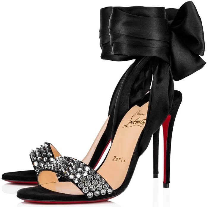 hristian Louboutin's black Krystal Du Desert sandals evoke a flirtatious sensibility with satin ties that drape around the ankle, fastening into a neat bow at the back