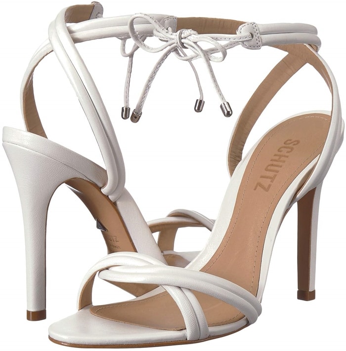 Plump, segmented straps entwine over the toe and wrap above the ankle of a towering white leather sandal finished at the front with a metal-tipped bow