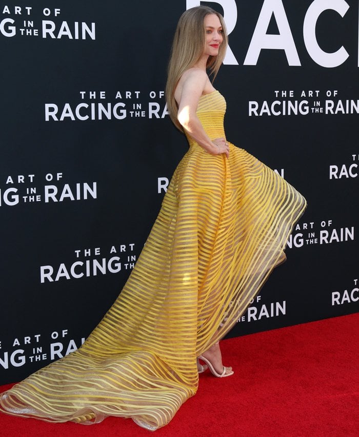 Amanda Seyfried dazzles in a strapless yellow Oscar de la Renta gown featuring sheer striped layers and a flowing hi-low silhouette