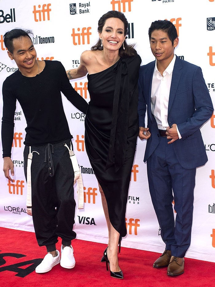 Angelina Jolie radiates elegance in a one-shoulder Ralph & Russo bow dress and Saint Laurent ‘Paris’ pumps, joined by sons Maddox and Pax—each showing off their unique style—at the First They Killed My Father premiere during TIFF on September 11, 2017