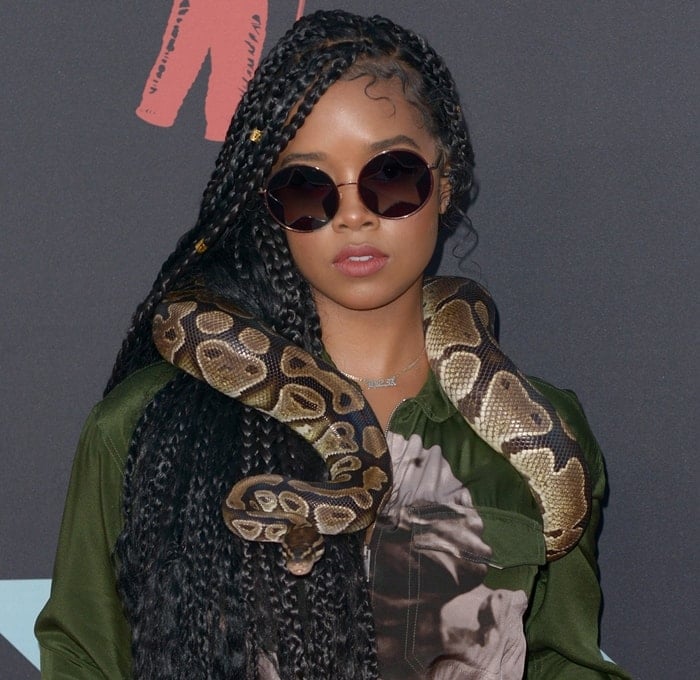 Gabriella Wilson, known professionally as H.E.R., with a python wrapped around her shoulders