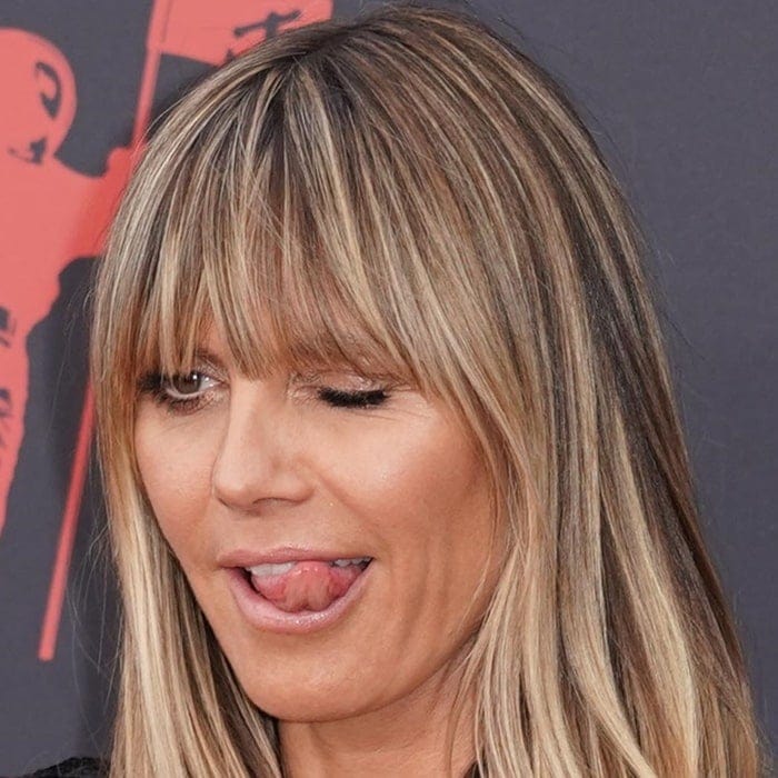 Heidi Klum plays to the cameras with a wink and playful tongue-out moment, her honey-blonde fringe softly framing a bronzed, glowing complexion