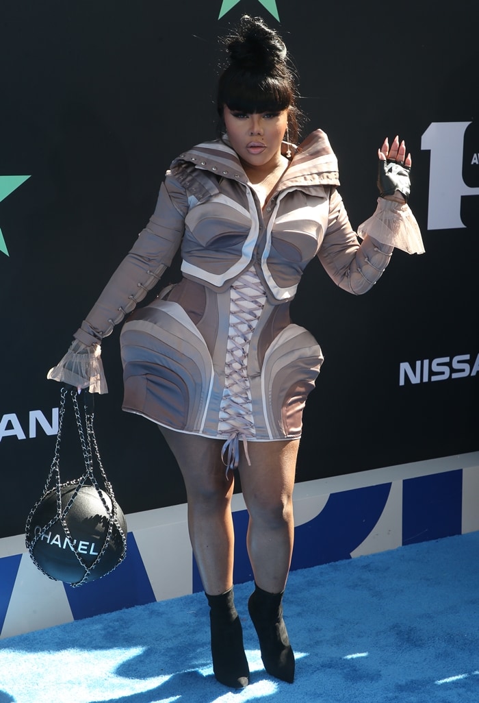 Lil' Kim showcases futuristic flair at the 2019 BET Awards in a sculpted mini dress by The Blonds, paired with black sock booties and a basketball-inspired Chanel purse