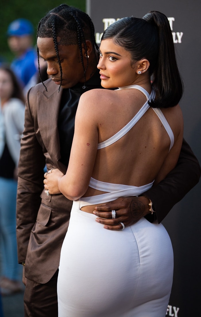 Kylie Jenner stuns in a backless white dress while Travis Scott complements her look in a sleek brown suit