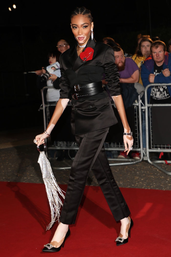 Winnie Harlow turns heads in a belted Prada Fall 2019 menswear suit, paired with crystal-embellished Roger Vivier satin heels at the 2019 GQ Men of the Year Awards