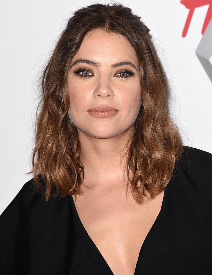 Ashley Benson wears her shoulder-length brown tresses in loose curls and sports nude makeup with smoky eyeshadow