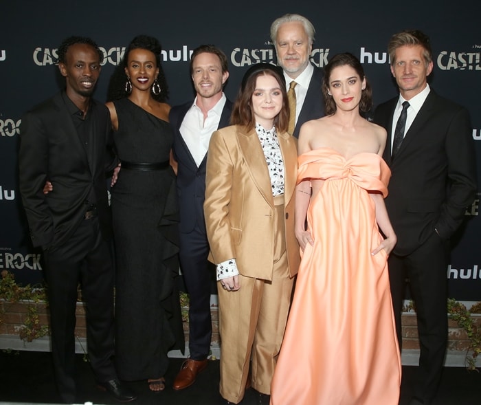 Lizzy Caplan poses with her Castle Rock co-stars, including Barkhad Abdi, Yusra Warsama, Matthew Alan, Elsie Fisher, Tim Robbins, and Paul Sparks, at the season two premiere in Los Angeles